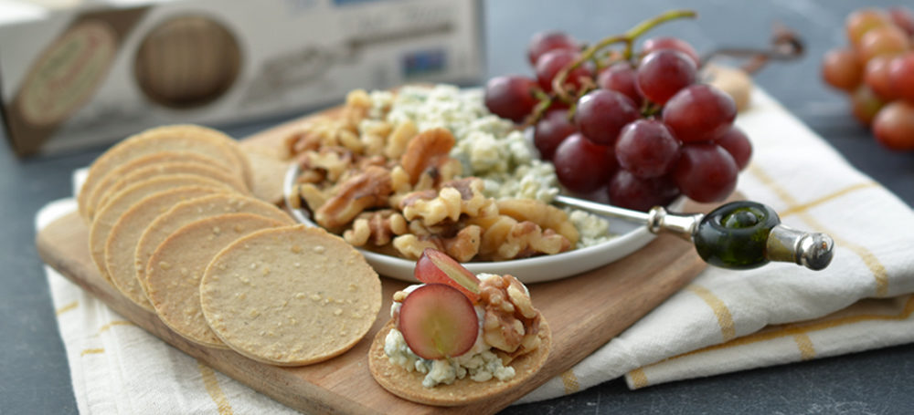 Toasted Oat Thins on a plate with cheese, walnuts and red grapes